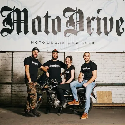 Четыре человека рядом с мотоциклом под вывеской MotoDrive