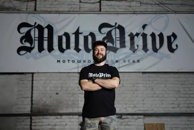 Мужчина со скрещёнными руками под вывеской MotoDrive