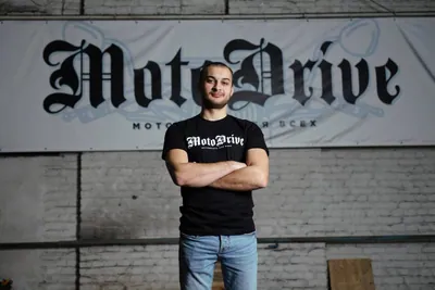 Мужчина в чёрной футболке MotoDrive и синих джинсах