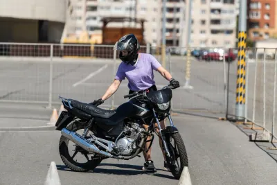 Ученица ведёт мотоцикл по разметке открытой учебной площадки