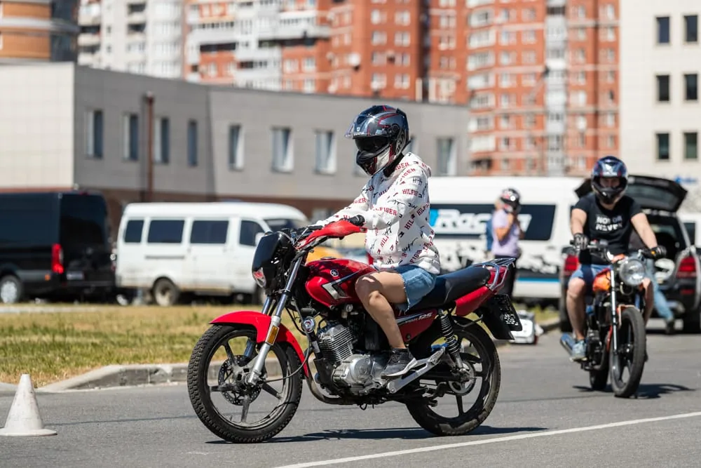 Ученики на мотоциклах выполняют упражнения на открытой площадке